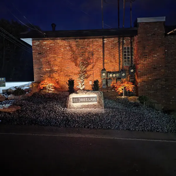Photograph taken at night depicts a custom made backlit sign made of metal by P&S Contracting and Landscape, for RL Ries Law. Aswell as therir Breathtaking landscape.