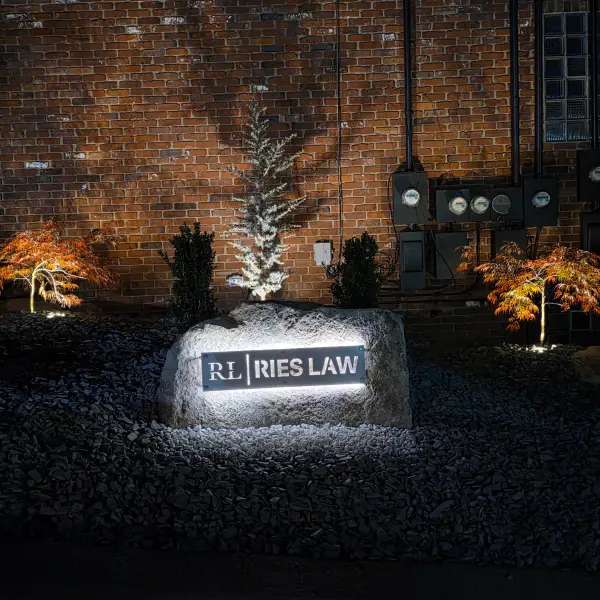Photograph taken at night depicts a custom made backlit sign made of metal by P&S Contracting and Landscape, for RL Ries Law